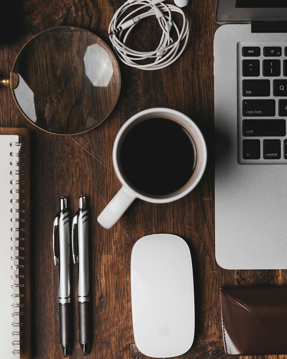 Desk with a notebook, coffee and a laptop